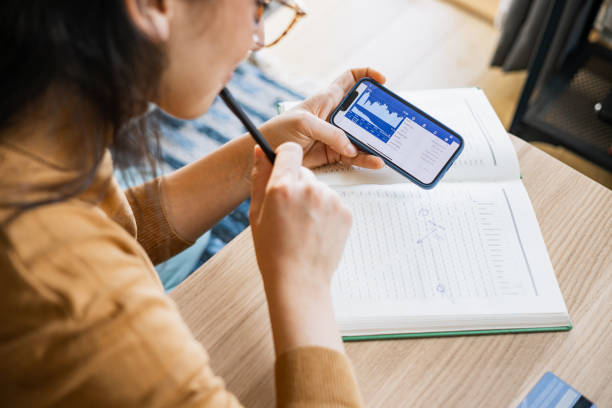 femme d’affaires analysant le marché boursier financier sur smartphone - stock certificate photos et images de collection