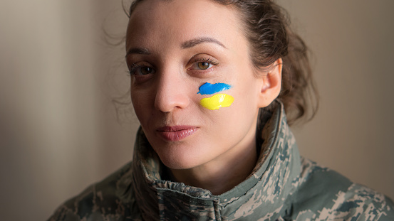Retrato interior de una joven con bandera ucraniana azul y amarilla en la mejilla con uniforme militar, reclutamiento obligatorio en Ucrania, conceptos de igualdad photo