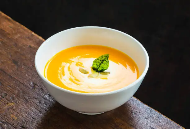 Photo of Pumpkin cream soup on dark background.