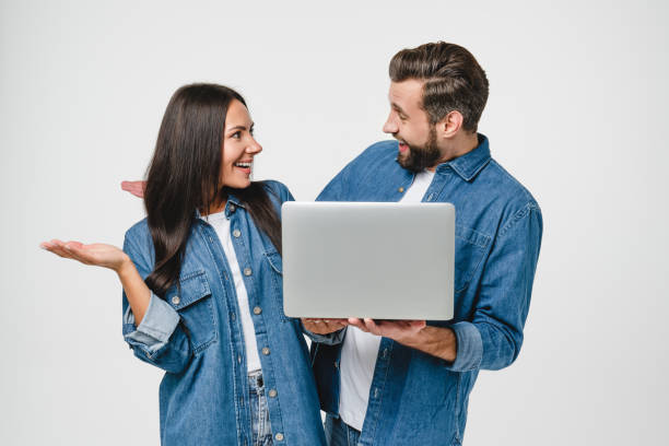 Impressed surprised caucasian young couple spouses wife and husband using laptop for online meeting, remote work, watching webinars, e-learning, playing games isolated in white Impressed surprised caucasian young couple spouses wife and husband using laptop for online meeting, remote work, watching webinars, e-learning, playing games isolated in white couple isolated wife husband stock pictures, royalty-free photos & images