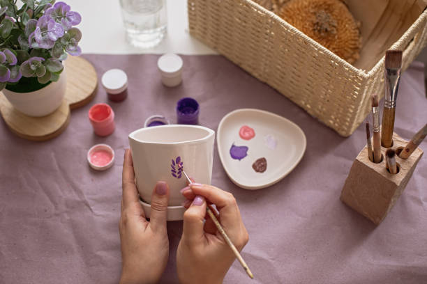 istock Womens hands paint a flower ceramic pot 1371165352