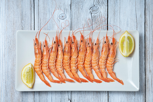 PRAWNS PLATTER ISOLATED ON WHITE WOODEN TABLE. SPANISH FOOD CONCEPT. TOP VIEW.