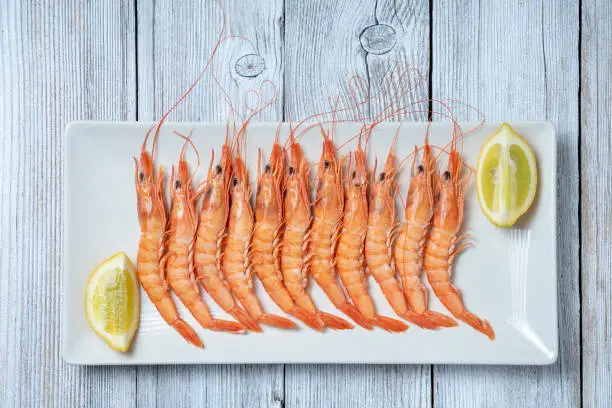 PRAWNS PLATTER ISOLATED ON WHITE WOODEN TABLE. SPANISH FOOD CONCEPT. TOP VIEW.