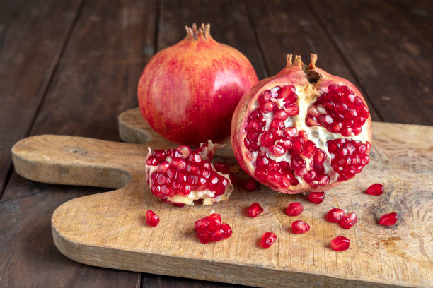 Pomegranates on the cutting board on the old wooden kitchen table. Vegan and vegetarian food. Healthy eating. Ecological agriculture concept. Pomegranates on the cutting board on the old wooden kitchen table. Vegan and vegetarian food. Healthy eating. Ecological agriculture concept. hand grenade photos stock pictures, royalty-free photos & images