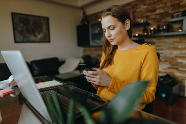 istock Woman using a smartphone and a laptop working from home 1371170810