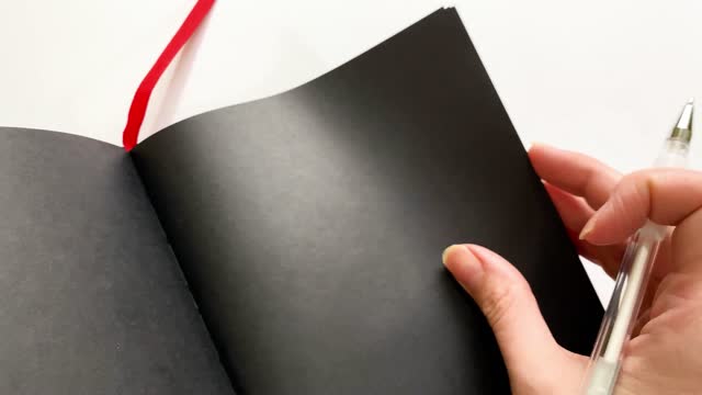 Close-up demonstration of a notebook with black paper for inscriptions in white ink