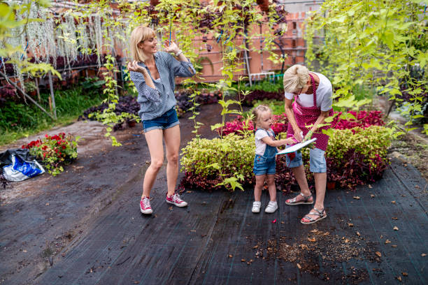 grandmother, daughter and granddaughter having fun together in botanical greenhouse - casual granddaughter farmer expressing positivity imagens e fotografias de stock