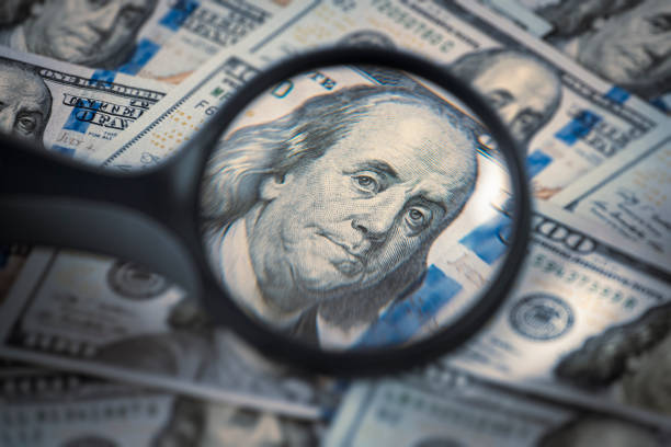 istock Benjamin Franklin in a magnifying glass and One hundred dollar bills 1371174334