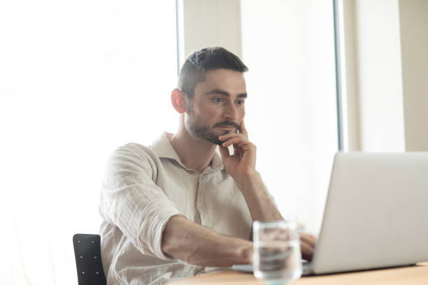 istock Young man with laptop in a room looking pleased 1371178696