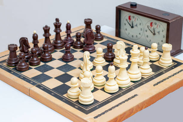 Chessboard with pieces. Arrangement of the pieces stems from an opening known as Queen's Gambit. The queen's gambit chess move explained on a chess board chess timer stock pictures, royalty-free photos & images