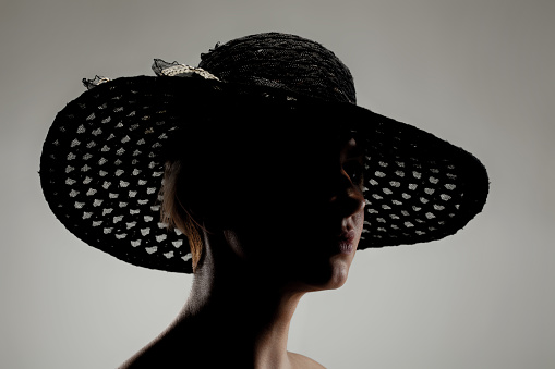 silhouette portrait of a caucasian girl with short hair wearing a hat