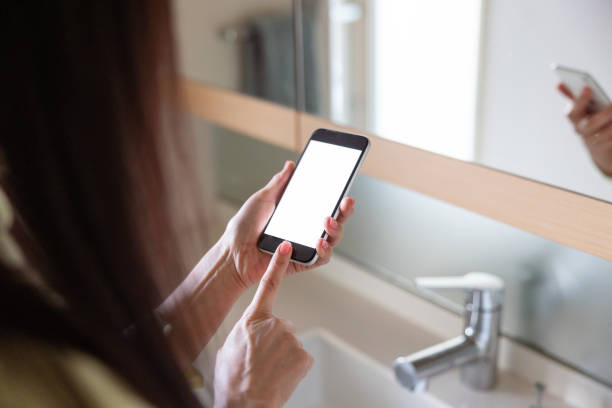 Woman ordering something and making reservation through smart phone app at bathroom