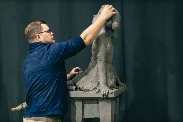 istock Man sculptor creates sculpt bust clay human woman sculpture. Statue craft creation workshop 1371188310