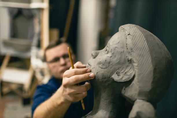 istock Man sculptor creates sculpt bust clay human woman sculpture. Statue craft creation workshop 1371188313