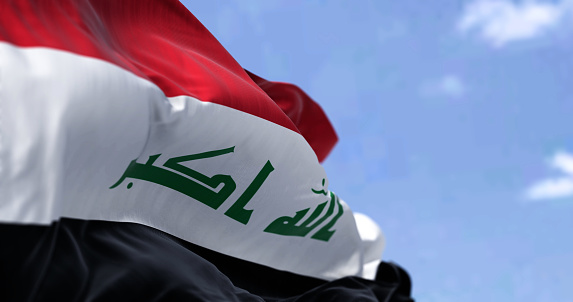 Detail of the national flag of Iraq waving in the wind on a clear day. Democracy and politics. Patriotism. Western asian country. Selective focus.