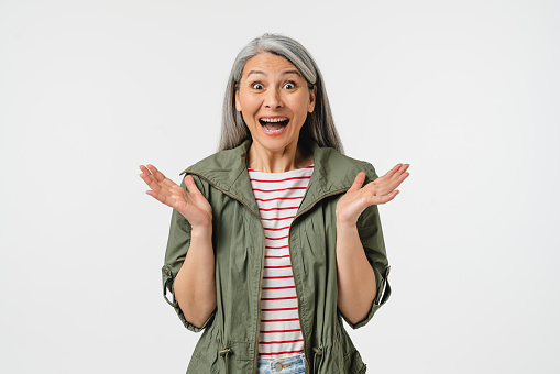 Extremely happy amused mature middle-aged caucasian woman in casual clothes and grey hair feeling shock impression, hearing good news, sale, discount, offer isolated in white background
