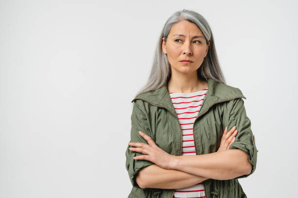 contemplación pensativa de una mujer caucásica madura de mediana edad con cabello gris y ropa casual sonando sus labios, sintiéndose ofendida aislada en un fondo blanco - portrait senior adult confusion women fotografías e imágenes de stock