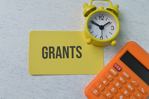 Clock, calculator and yellow card with text GRANTS