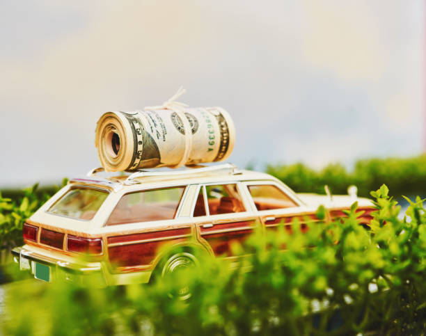 Vintage station wagon with roll of cash on it's roof rack in leafy setting Vintage station wagon with roll of cash on it's roof rack in leafy setting cash for cars stock pictures, royalty-free photos & images