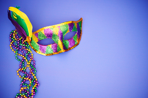 istock Background for Mardi Gras with glittery masquerade mask and vibrant beads on a purple background 1371202288