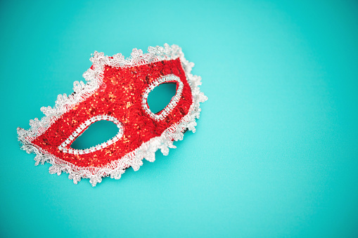 Background for Mardi Gras with glittery red masquerade mask on a teal background