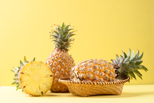 Fresh pineapple fruit in basket on yellow background, Tropical fruit