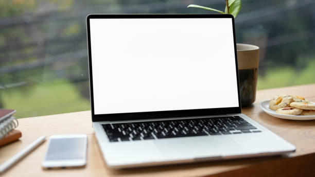 istock Laptop computer blank screen mockup and accessories on wooden table. 1371208756