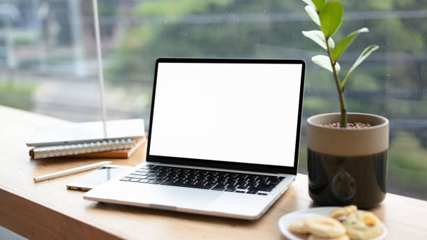 istock Laptop computer white screen mockup on wooden table 1371208760