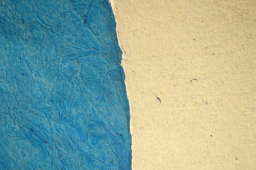 Horizontal empty contrast divided background with two halves by tearing the vibrant turquoise  blue coloured grunge textured paper with texture and wrinkles and revealing a plain light brown or beige layer