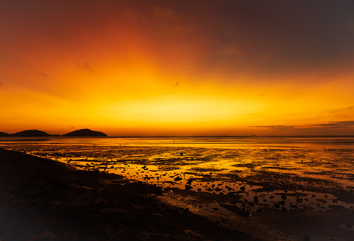 Scene of beautiful orange sky in the morning at Saphanhin public beach, Phuket, Thailand.