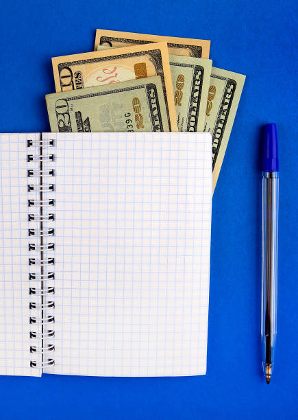 Notepad with a Money Writing Pad with a Money on the Blue Paper Background closeup money memo stock pictures, royalty-free photos & images