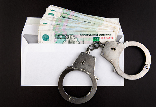 Handcuffs on the Envelope with a Russian Rubles on the Black Paper Background
