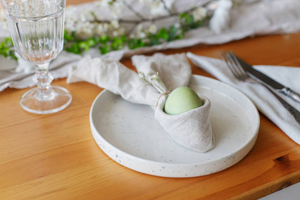 istock Easter egg in bunny napkin on plate with cutlery, bunny, spring flowers and rustic cloth on wooden table. Stylish Easter brunch table setting. Holiday arrangement and eco friendly decorations 1371226607