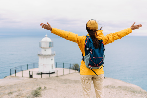 Traveler with his tourist backpack is standing against a sea background. Travel, tourism and active lifestyle concept. Portrait of a female traveler on the background of the blue sea. Copy space