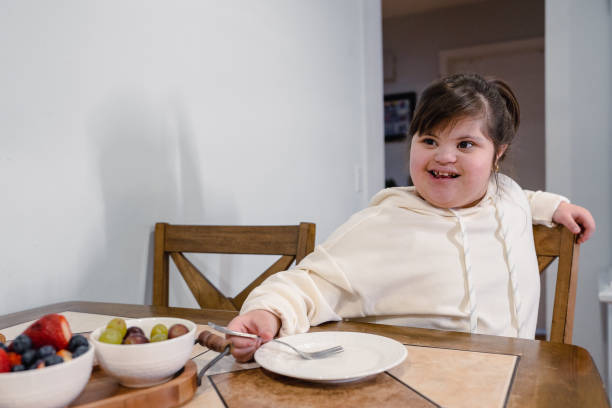 Girl with down syndrome doing eating fruits stock photo