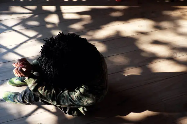 Top view alone Vietnamese woman sit indoor on wooden floor with drop shadow from door by sunny afternoon, people wear soldier clothes and ruffled hair