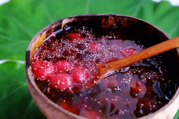 Top view red sugared strawberries in bowl that make from coconut shell on green leaf, red fresh Da Lat fruit for summer day, yummy food