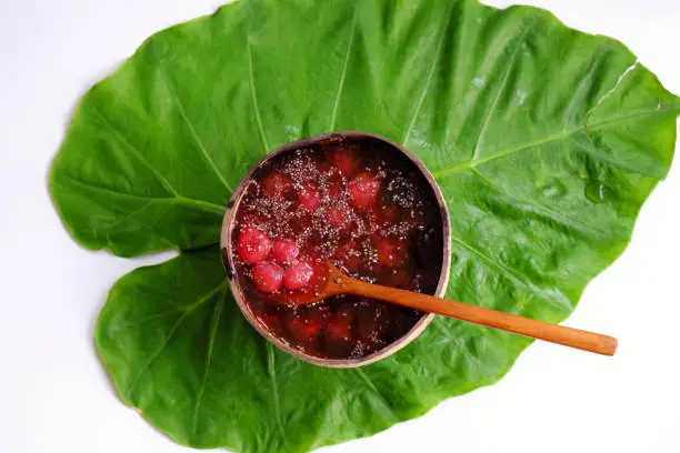 Top view red sugared strawberries in bowl that make from coconut shell on green leaf, red fresh Da Lat fruit for summer day, yummy food