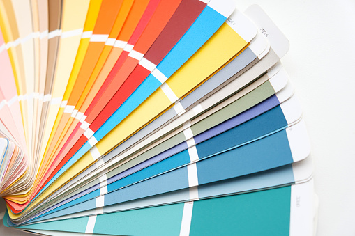 Color guide close up. Assortment of colors for design. Colors palette fan on a white concrete wall background. Graphic designer chooses colors from the color palette guide. Coloured swatches catalogue