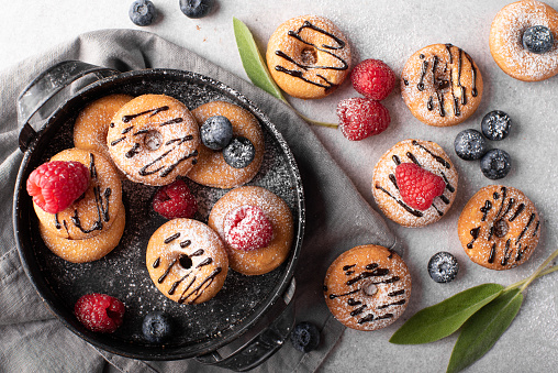small homemade donuts with chocolate and berries on a gray plate
