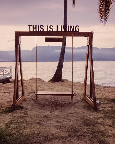 One empty wooden swing on a beach in the afternoon.