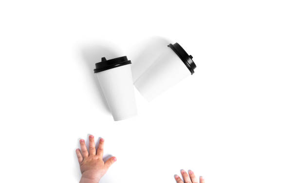 White disposable cups with a black lid isolated on a white background. Child hands. Paper cups