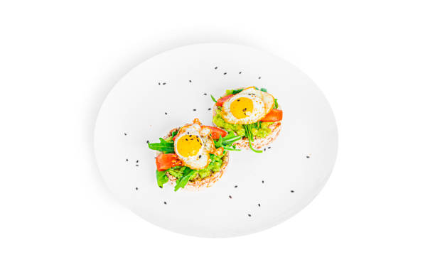 istock Crispbread sandwich with guacamole, arugula, tomatoes and quail egg isolated on a white background. Bruschetta with avocado. Healthy breakfast 1371244690
