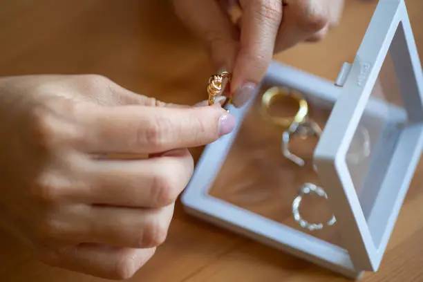 Women's hands choosing golden ring from her jewelry box