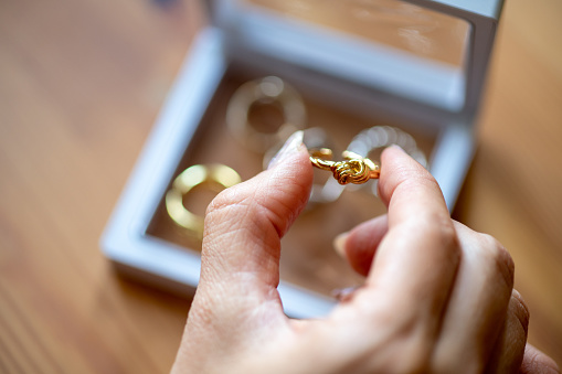 Close-up of women's hands choosing golden ring from her jewelry box.