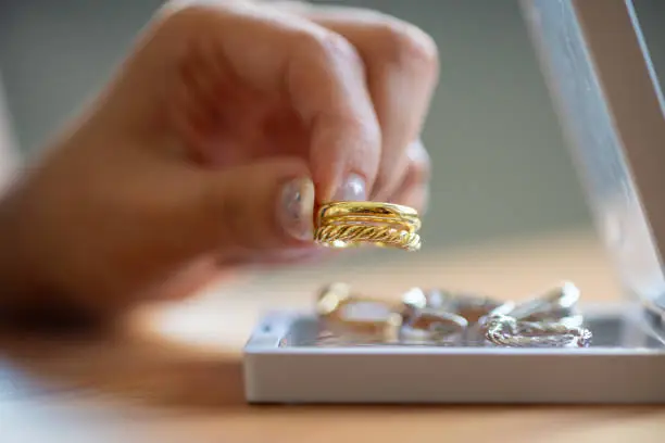 Women's hands choosing golden ring from her jewelry box