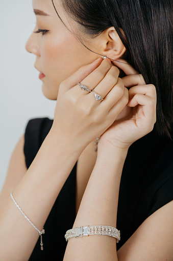 Women's jewelry. Close-up of a mother-of-pearl earring on a woman's ear. Hand with a beautiful French manicure.