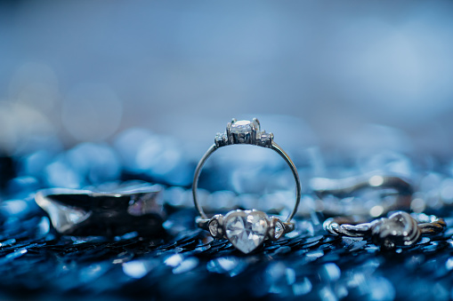 Close-up engagement diamond rings on dark blue background with bokeh.  Modern fashion jewelry