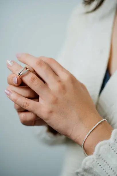 Close-up shot of a Asian woman put on a silver ring on her finger with white background.