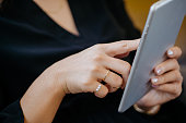 Close-up of woman using digital tablet with luxury accessories such as silver ring